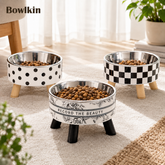 Three elevated pet bowls by Bowkin on a light rug in a bright room. The bowls are shown with dry kibble, with two white bowls featuring black polka dots and one white bowl featuring a black-and-white checkered pattern.